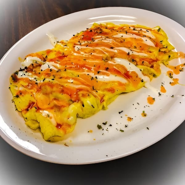 A plate of scrambled eggs drizzled with white and orange sauces, sprinkled with herbs.
